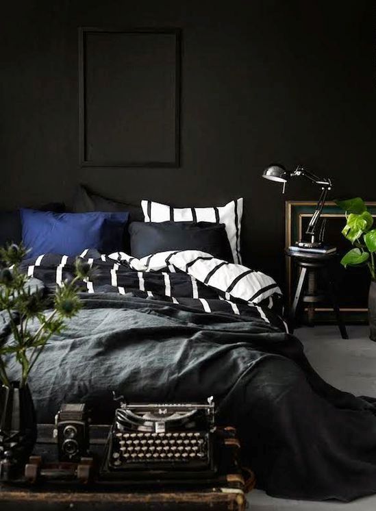 a moody bedroom with black walls, vintage finds and touches of fresh greenery for freshness