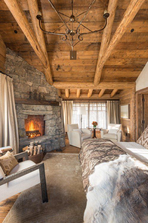 a cabin bedroom with touches of wood and stone, with faux fur and metal chandelier