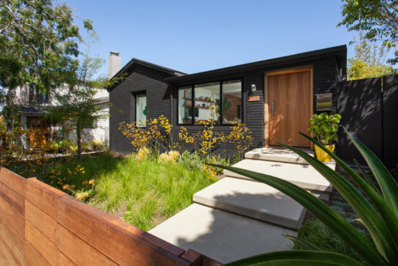 The backyard of this addition is done with some greenery and blooms plus potted plants