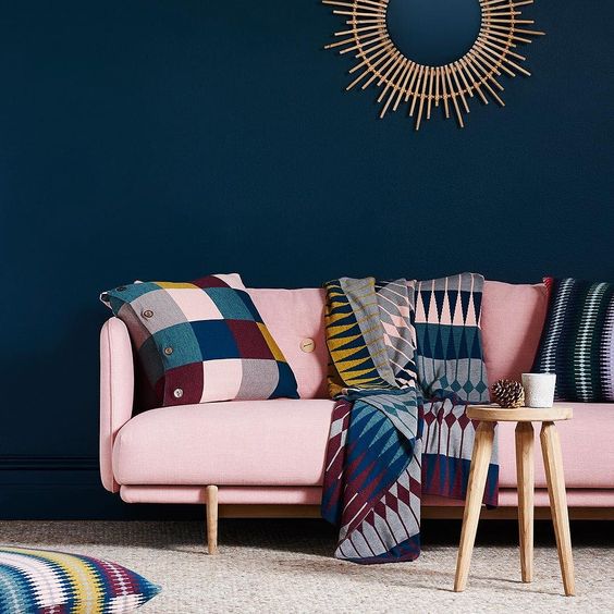 a sophisticated living room with a navy statement wall, a bold modern pink couch and colorful accessories