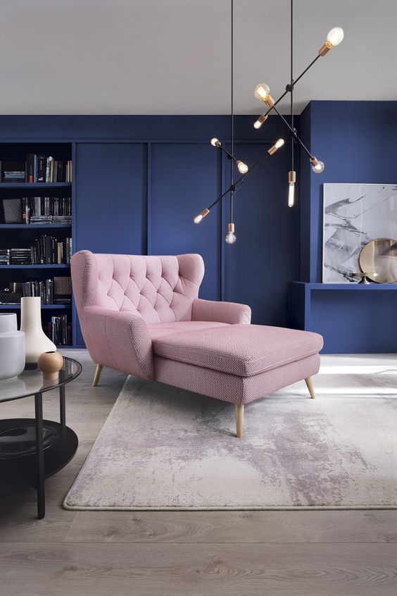 a mid-century modern living room with navy walls and a blush lounger looks bold and fresh