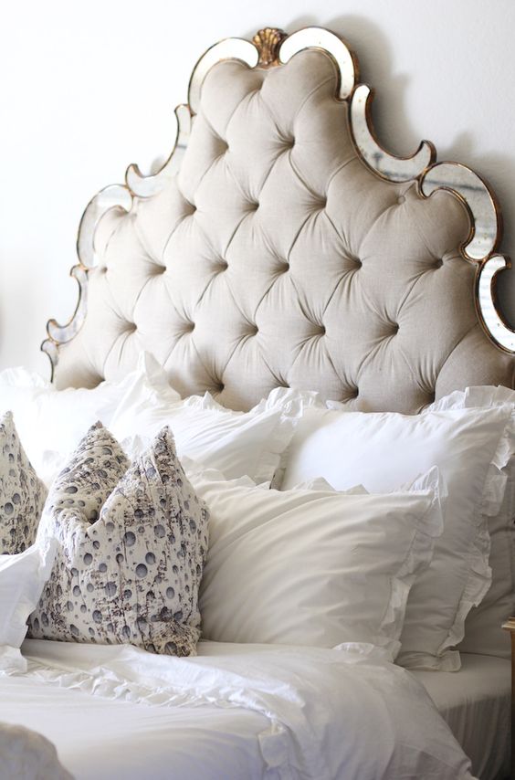 a neutral cutout tufted headboard with mirror touches is a chic and unusual idea