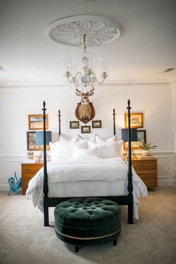 a dark green velvet upholstered sofa adds color and texture to the neutral bedroom