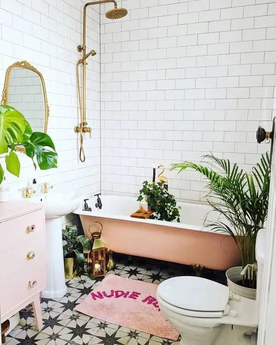 a beautiful tropical bathroom with white subway and black and white star tiles, a peachy pink bathtub, a blush vanity and a free-standing sink