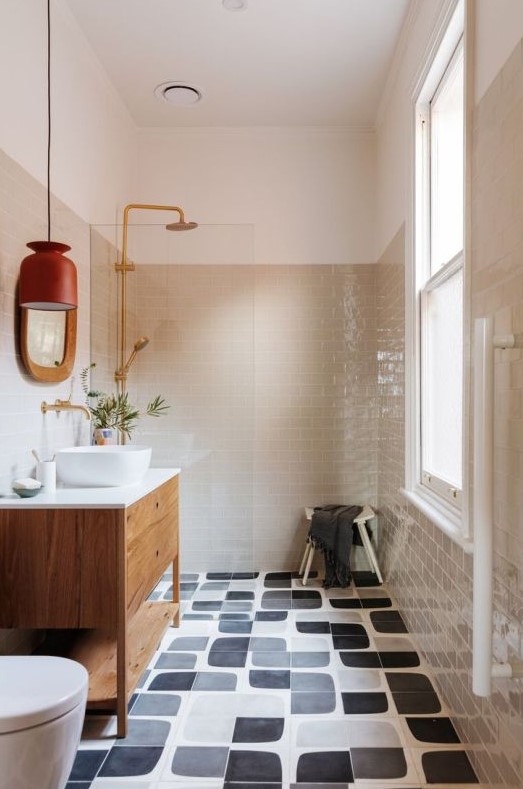 a mid-century modern bathroom with grey and graphic black and white tiles, a stained vanity, white appliances and gold fixtures