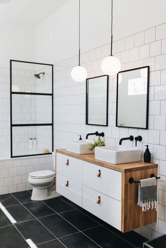 a mid-century modern bathroom with long grey tiles and white square ones, black frames and a floating vanity with two sinks
