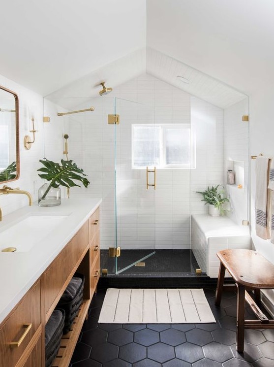 a mid-century modern bathroom with white skinny and black hex tiles, a stained vanity and a bench, gold fixtures
