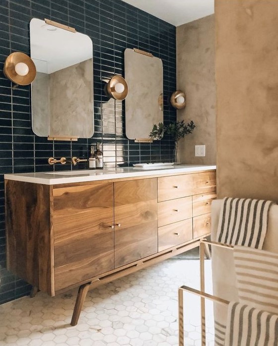 a refined mid-century modern bathroom with plaster walls, a wooden vanity, marble hex tiles and a navy skinny tile wall plus brass touches