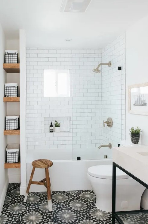 a stylish modern bathroom with white subway and printed tiles, a sink on a stand, a white tub and a wooden stool