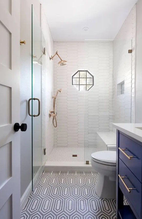 a tiny bathroom with white and printed tiles, a navy vanity, white appliances, brass fixtures and black touches