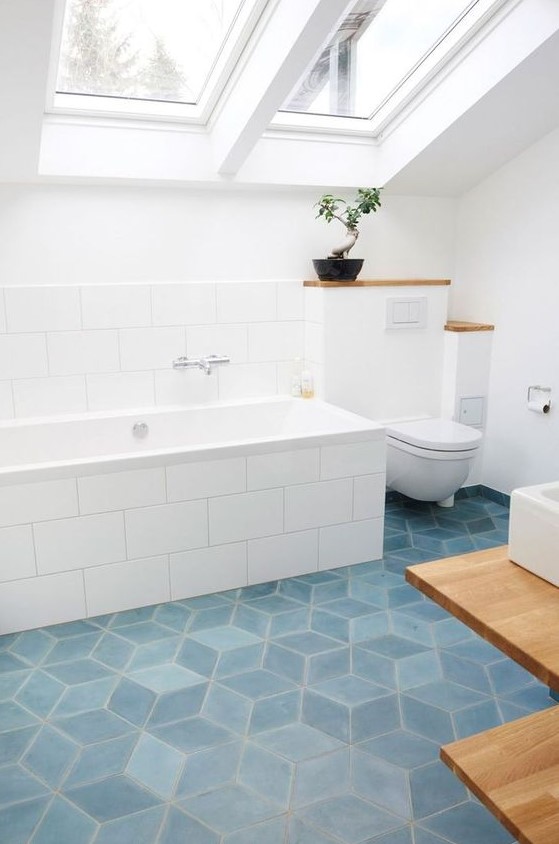 an airy attic bathroom with blue geometric tile floor, large scale subway tiles and white appliances