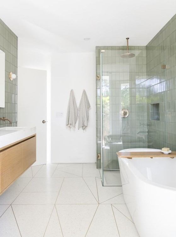 an airy mid-century modern bathroom with white geo and green skinny tiles, a floating vanity and a tub, a shower space