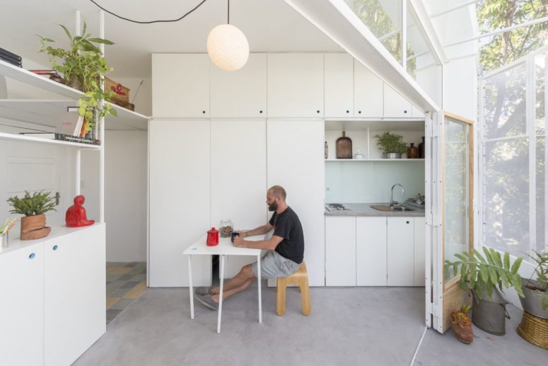 a small eating space is a must for a tiny apartment's kitchen The apartment features a white sleek kitchen with a small eating space that can be hidden
