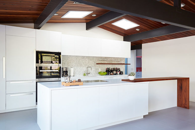 The kitchen is done with white sleek cabinets, a marble penny tile backsplash