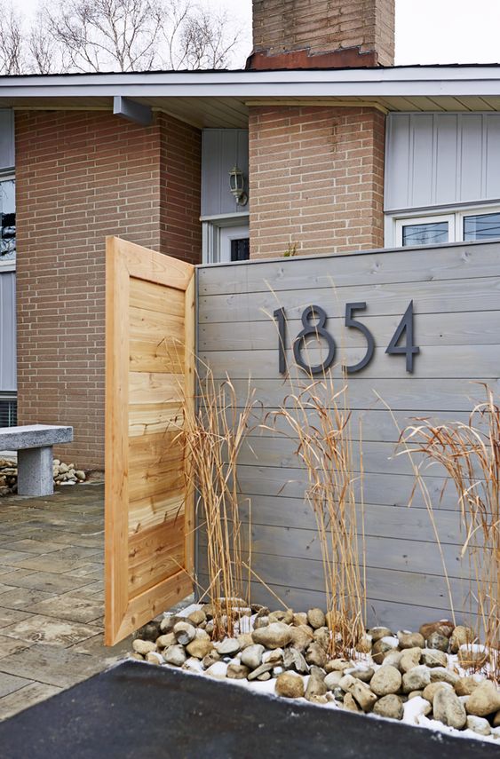 house numbers placed on the wood plank wall in the front yard space is a cool idea