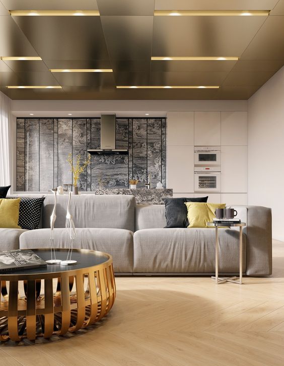 a contemporary living room is spruced up with a gorgeous gold ceiling with a geometric design and gold furniture