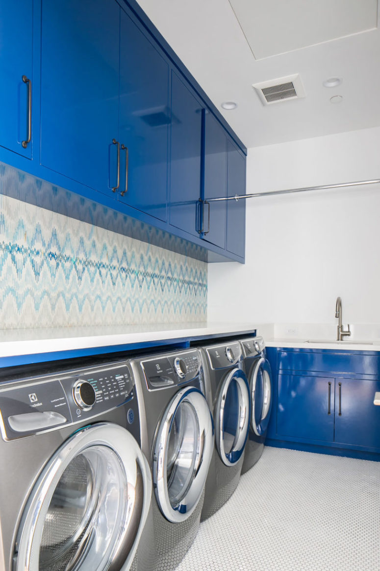 a large and functional laundry room design The laundry room continues the blue and white color scheme, which can be seen throughout the house