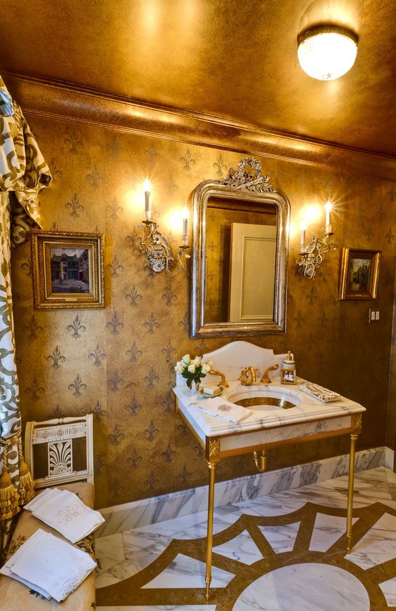 a gorgeous and refined powder room with a gold ceiling and gold furniture legs and faucets