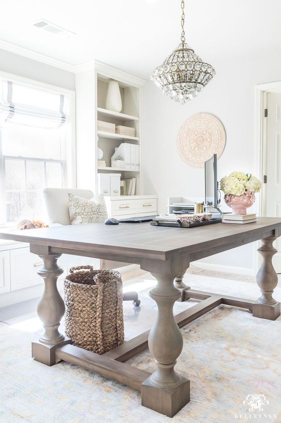 an oversized rustic vintage table used as a desk looks very contrasting to the modern home office