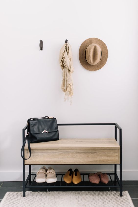 a small modern bench with black metal framing and a large seat with hidden storage