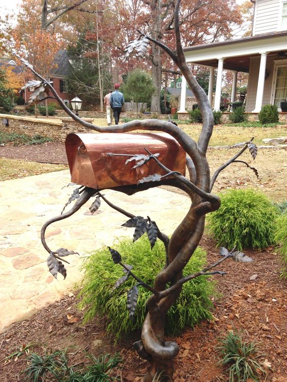 a curved metal tree with leaves and a copper box is a gorgeous and mysterious idea