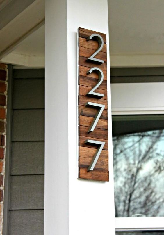 a stylish modern house number display with rich-colored wooden planks and modern numbers attached to the corner of the house