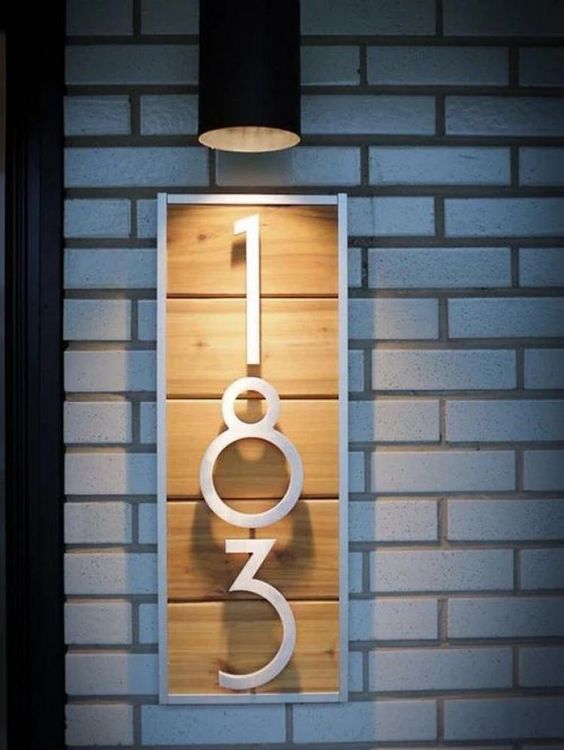 a modern house number sign of light-colored wood, white painted numbers and frame for a bold look
