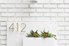 a minimalist all-white house number design with succulents