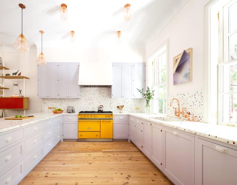 a lilac kitchen accented with a bright yellow cooker and a polka dot backsplash plus brass lamps