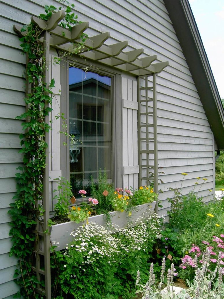 a neutral wooden window box planter with colorful blooms and flowers around it, too