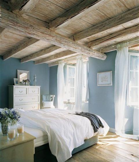 a vintage-inspired bedroom with a rough and rustic wooden ceiling with lots of beams that takes over the space