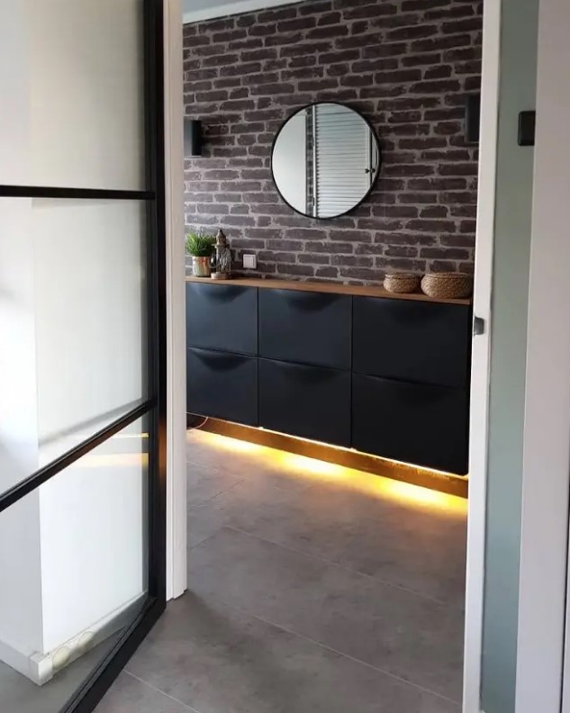 a black IKEA Trones piece attached to the wall, with a stained countertop and built-in lights underneath