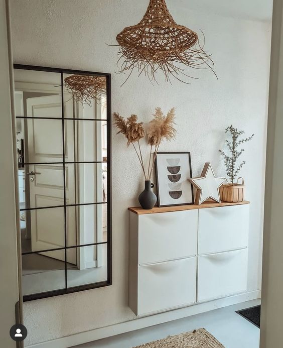 a boho entryway with a framed mirror, a white Trones with a wooden countertop, some decor, a star and grass