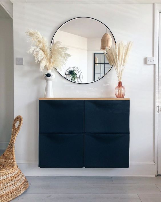 a boho entryway with a navy Trones piece and a wooden countertop, grasses and a round mirror is awesome