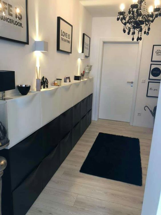 a contrasting entryway with a black and white Trones piece with lamps and decor, a gallery wall and a black chandelier