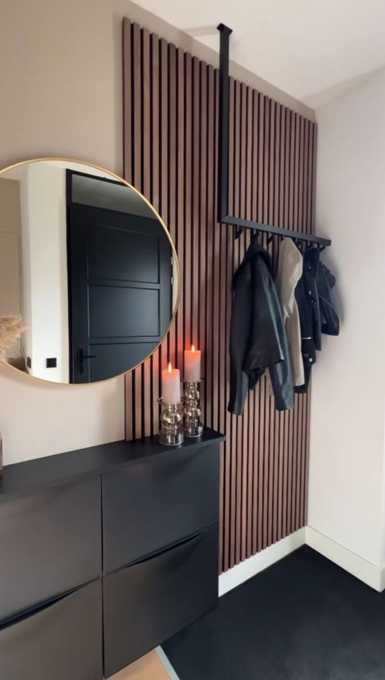 a modern entryway with a black Trones piece, a rack, a round mirror and a wooden slat accent