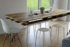 03 a contemporary dining table with a pallet as a tabletop and hairpin legs on casters plus modern white chairs