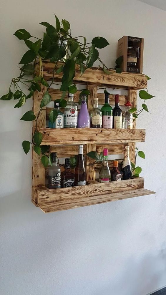 a stained wine rack of pallet wood features enough space for bottles and potted greenery on top