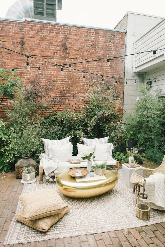 make your outdoor lounge inviting placing a cool boho rug on the floo, add pillows and wicker furniture