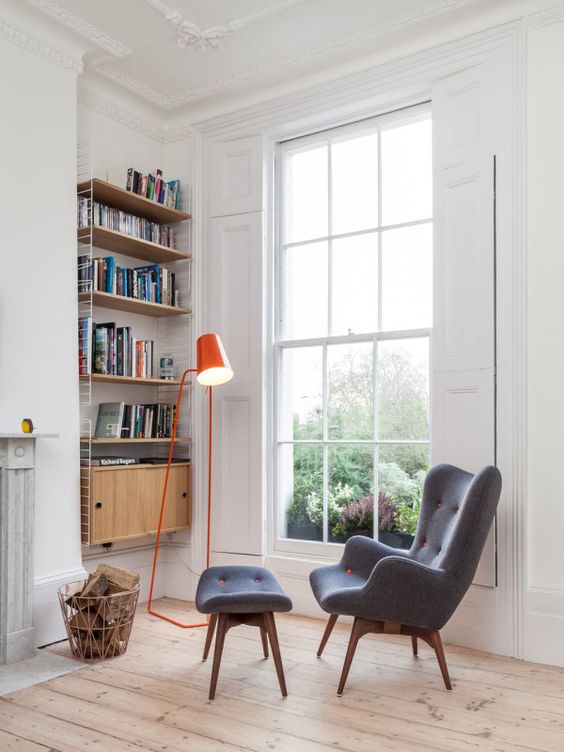 a retro-inspired grey wingback chair with a matching footrest and touches of orange plus a bold orange lamp