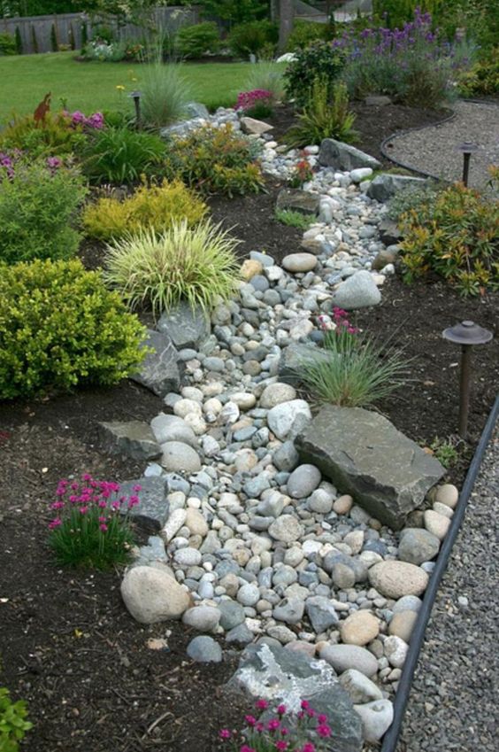 a beautiful and low maintenance garden incorporating a river rock dry stream with herbs and blooms around