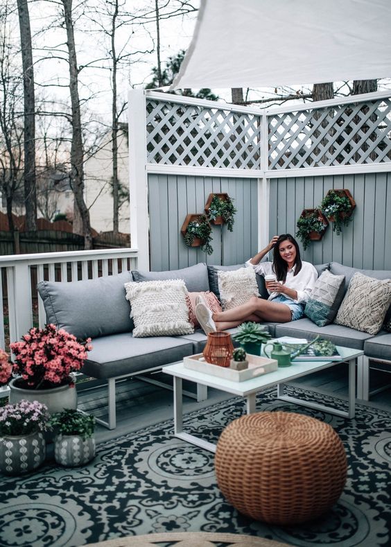 a grey boho deck with touches of natural green and pink blooms plus a wicker ottoman