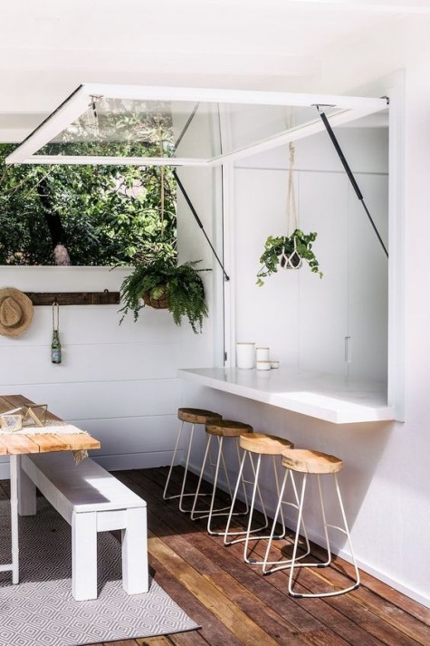 a garage-style window with a minimalist sleek tabletop and some wooden and metal stools