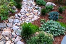 15 a dry stream idea with large pebbles and rocks plus green grasses around and some blooms