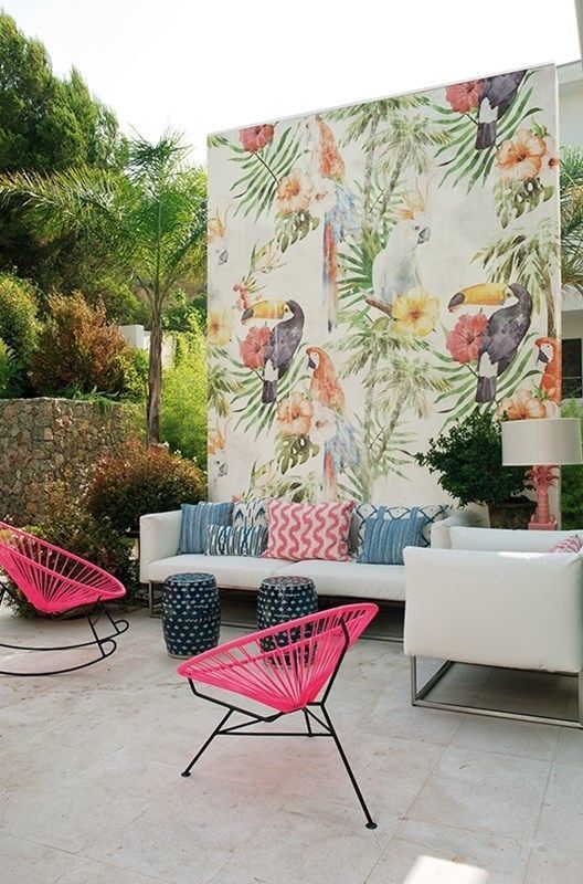 một hiên nhiệt đới đầy màu sắc với một chiếc ghế sofa màu trắng và gối đầy màu sắc, ghế màu hồng nóng, một bức tường màu nước tươi sáng và phân nhỏ một hiên nhiệt đới đầy màu sắc với một chiếc ghế sofa màu trắng và gối đầy màu sắc, ghế màu hồng nóng, một bức tường màu nước tươi sáng và phân nhỏ