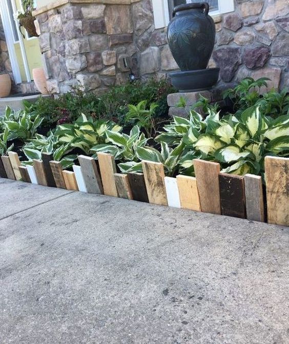 simple and catchy garden bed edging done with mismatching woodne planks in various colors