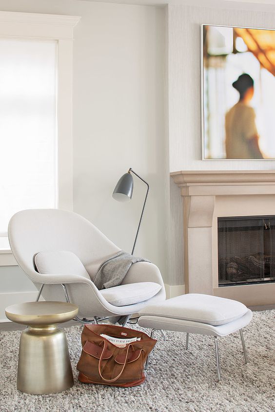 a comfy mid-century-inspired white chair and a matching footrest, a metal floor lamp and a metal side table for a comfy nook