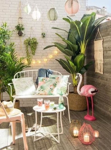một sàn nhỏ nhiệt đới với cây xanh trong chậu, một con hồng hạc hồng, đèn lồng nến đầy màu sắc, đồ nội thất rèn màu trắng thanh lịch và đèn một sàn nhỏ nhiệt đới với cây xanh trong chậu, một con hồng hạc hồng, đèn lồng nến đầy màu sắc, đồ nội thất rèn màu trắng thanh lịch và đèn