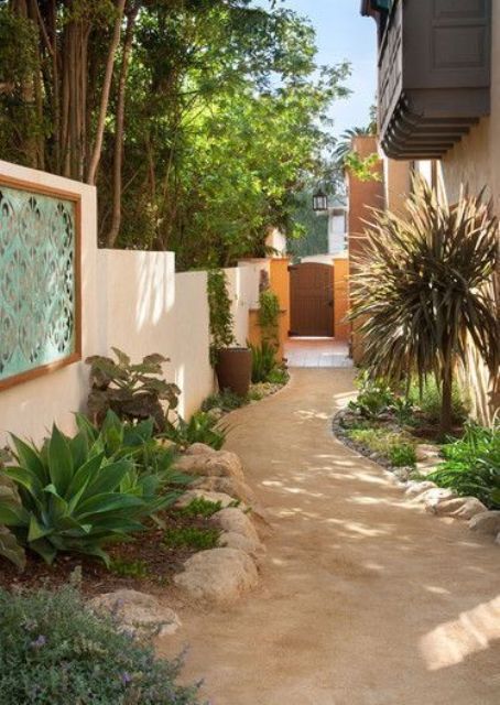 a side yard done with neutral decomposed granite and some flower beds