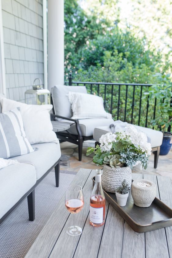 a yarn-covered planter and a concrete one, a lantern and some wine and glasses